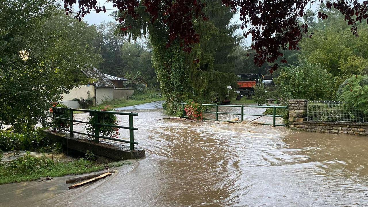 Eine überflutete Brücke über einem Bach.